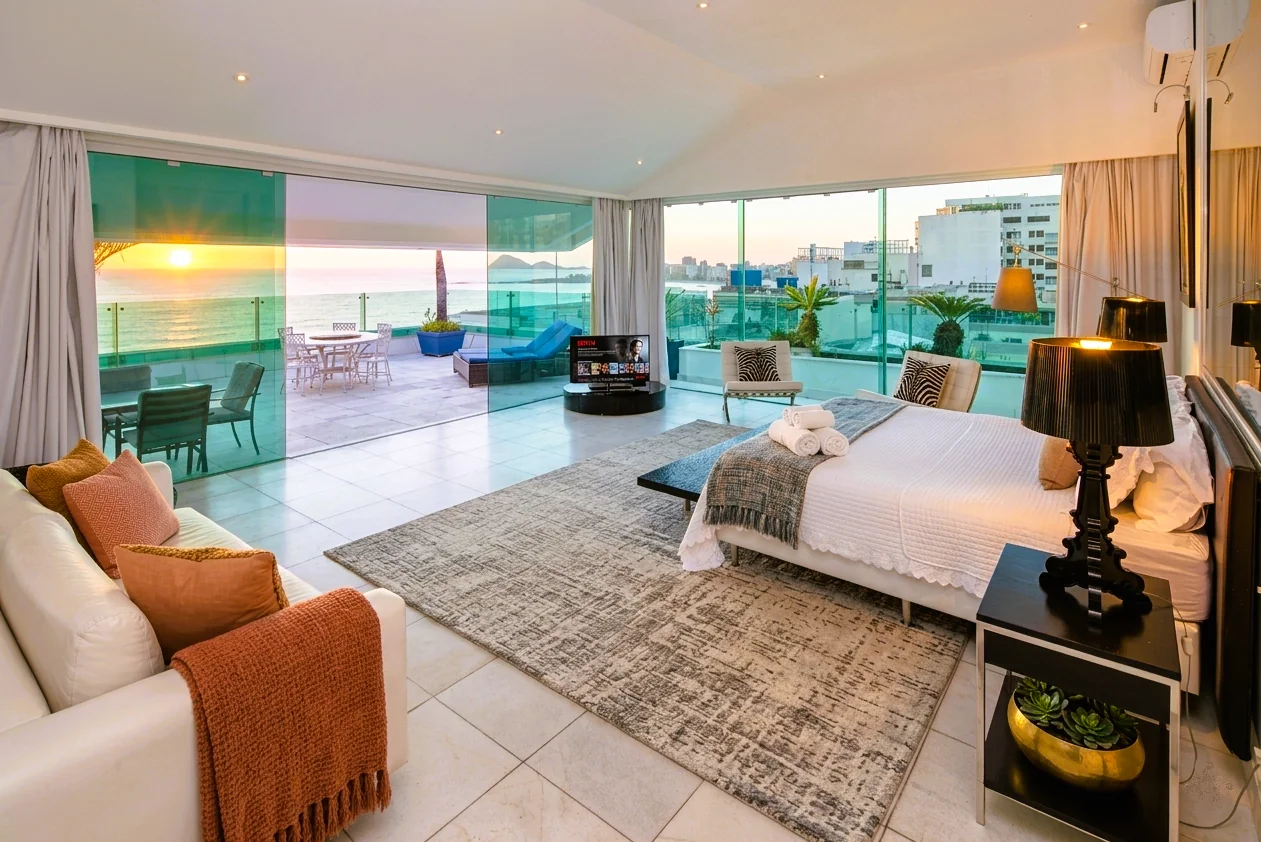 Copacabana penthouse bedroom after Cavmir interior redesign and 5:15 AM sunrise photography — styled bed, warm textures, ocean view